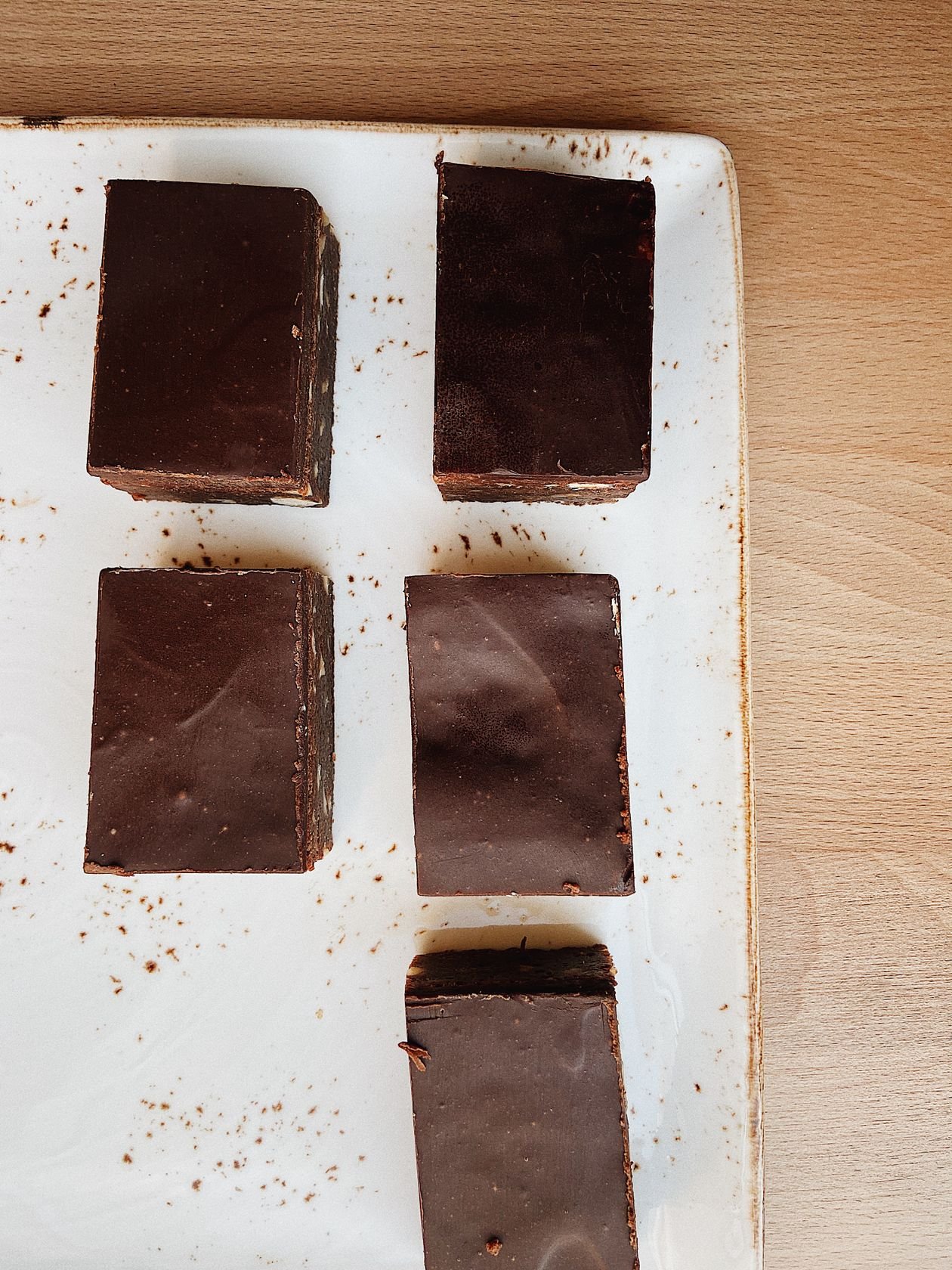 Five dark chocolate fudge squares arranged on a white plate