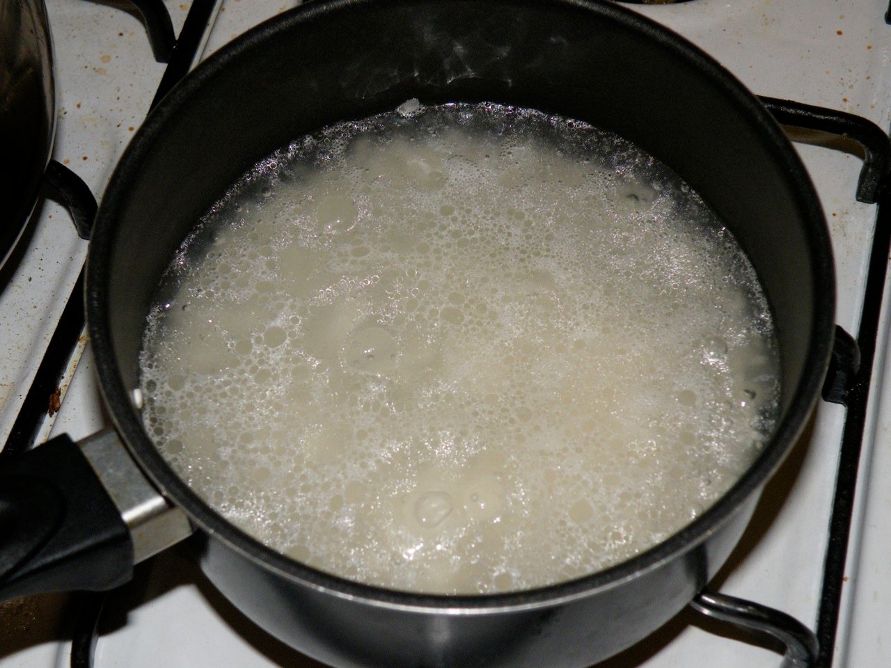 Rice boiling in a pot of starchy water on a stove