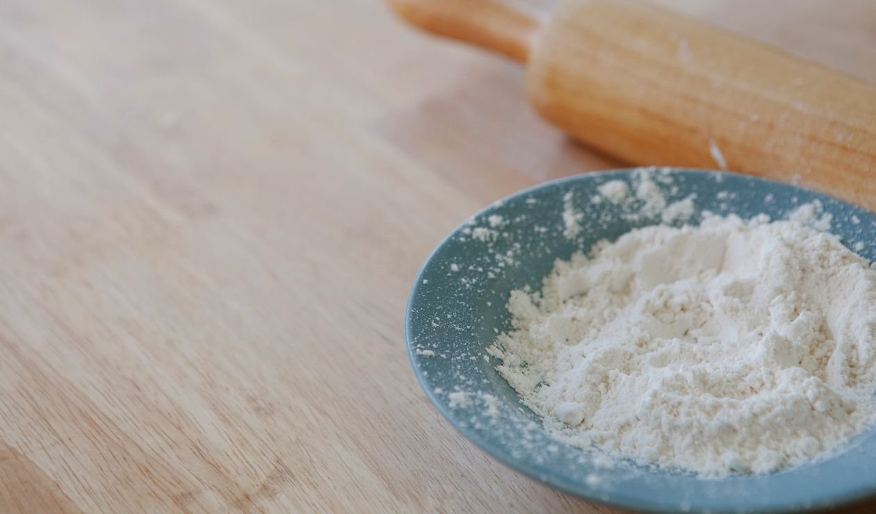 A bowl of white powder on a wooden kitchen counter