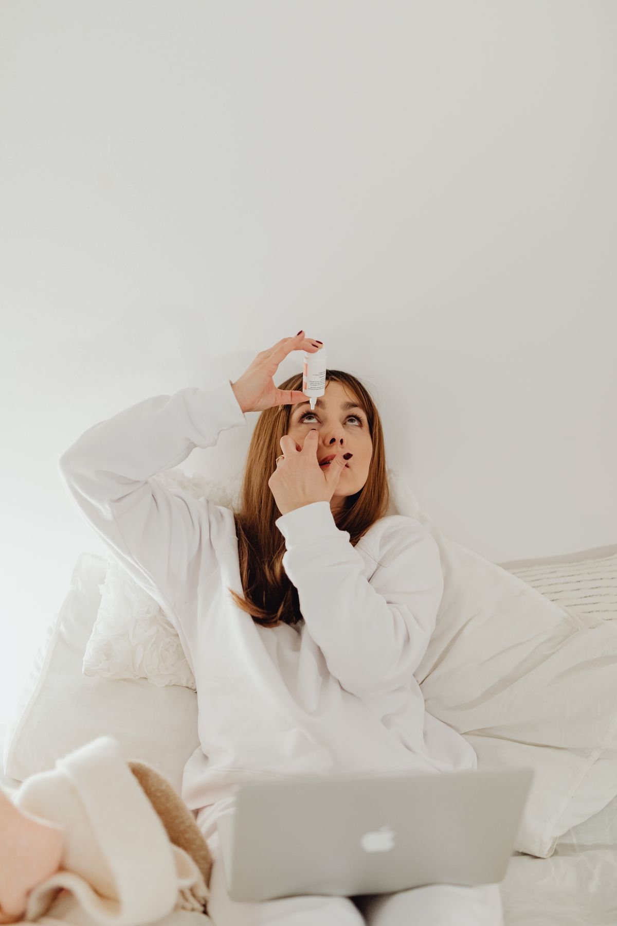 Woman applying lubricating eye drops at home before going out in cold weather