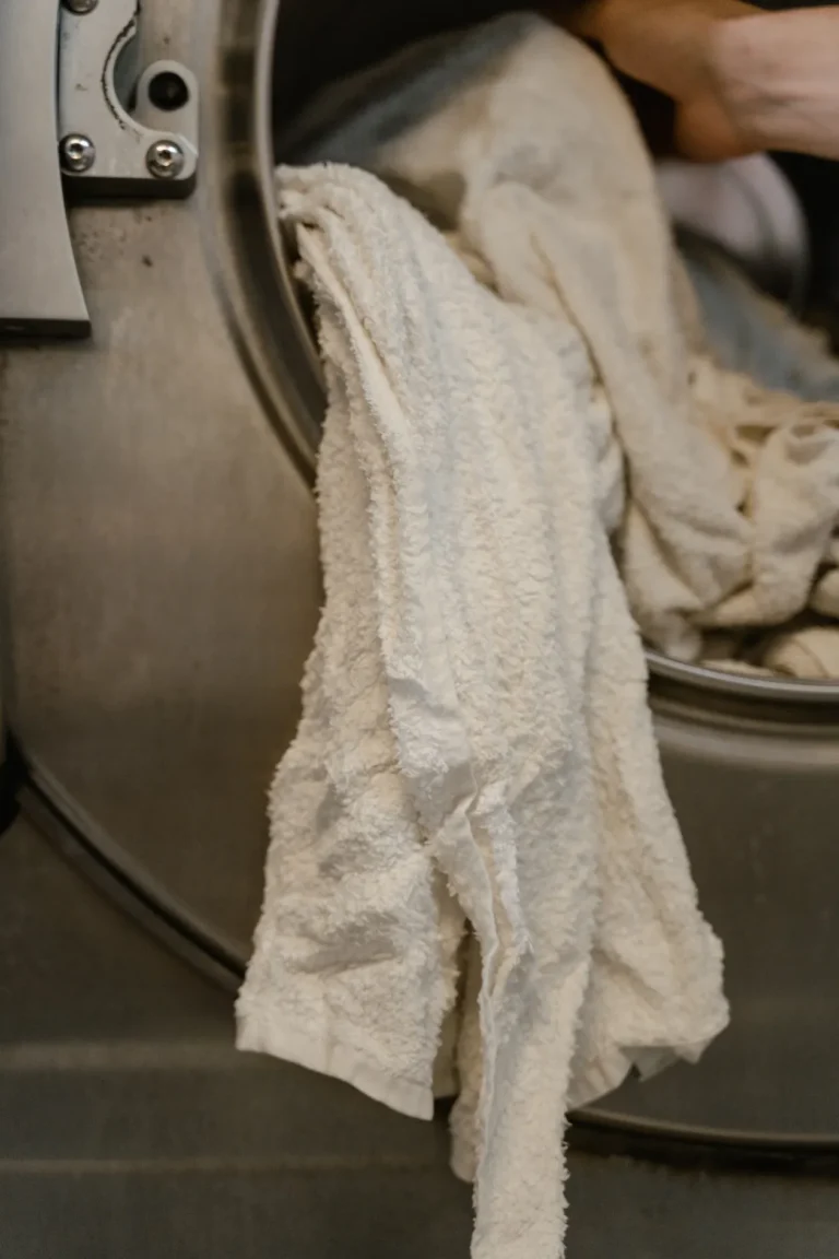 White towels being loaded into a washing machine drum