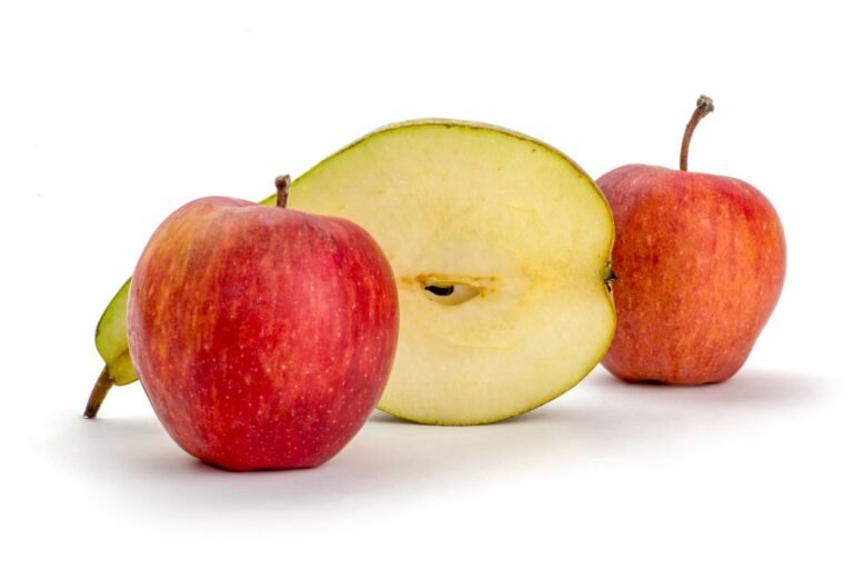 How to Keep Cut Apples From Browning: 7 Methods That Actually Work Whole and halved red apples on a white background showing fresh cut apple flesh