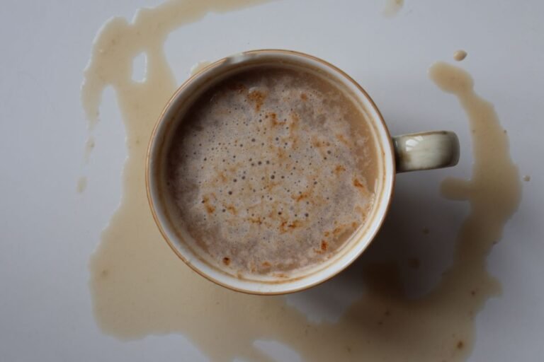 Overhead view of a spilled cup of coffee on a white surface