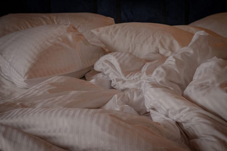 White duvet bunched up and rumpled on an unmade bed