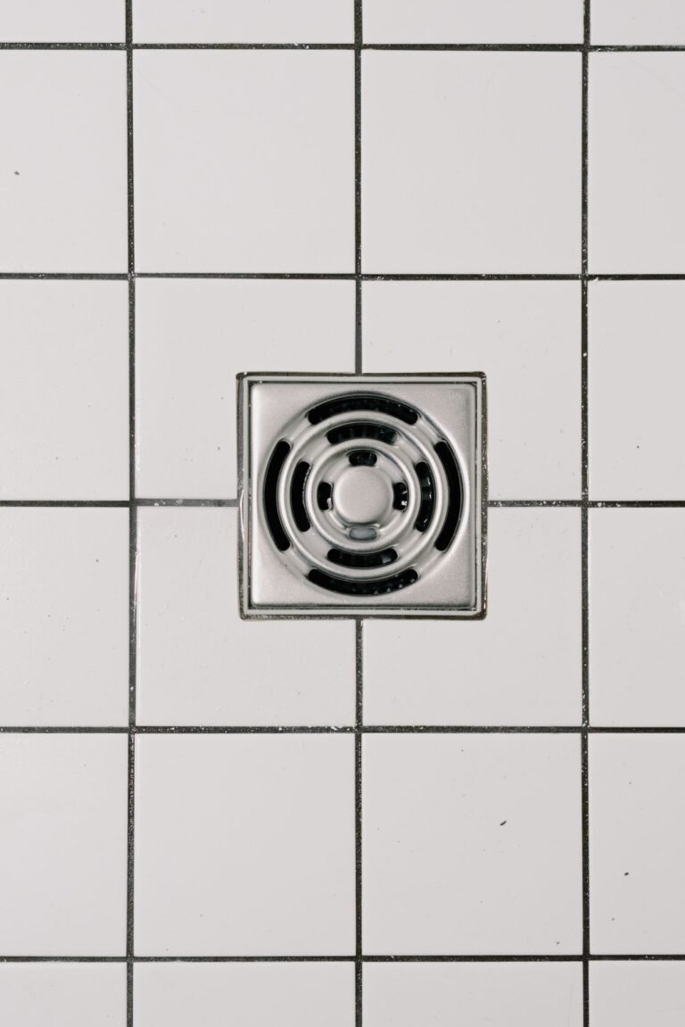 Close up view of a shower drain set in white shower tiles