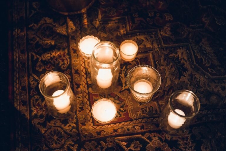 Lit candles in glass holders sitting on a patterned rug
