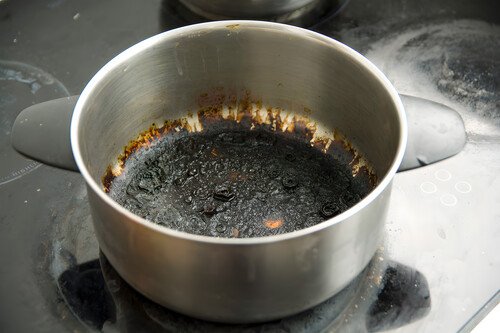 How to Clean a Burnt Saucepan Without Scrubbing: 5 Easy Methods Burnt blackened saucepan with scorched residue sitting on a stove