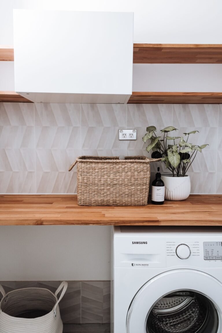 Why Does My Washing Machine Smell Like Rotten Eggs: 8 Causes and Fixes White front load washing machine in a tidy laundry room with wooden worktop and wicker basket