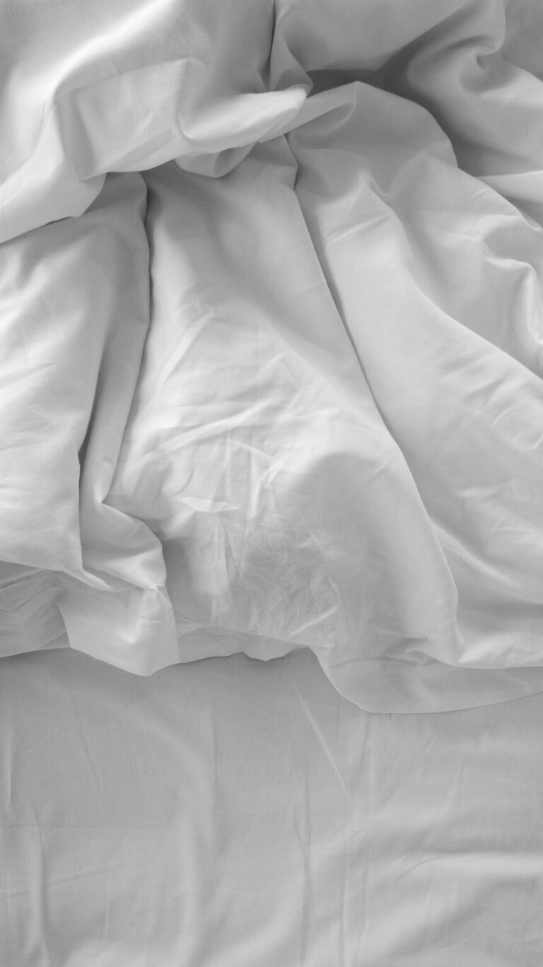 Rumpled white fitted sheet slipping off the mattress corner