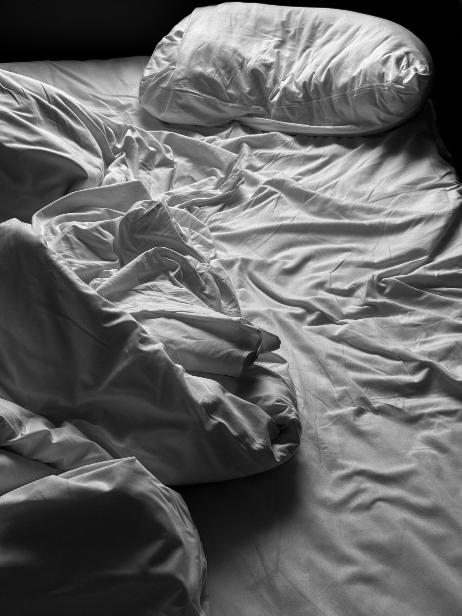 Bed with loose white sheets after restless sleep