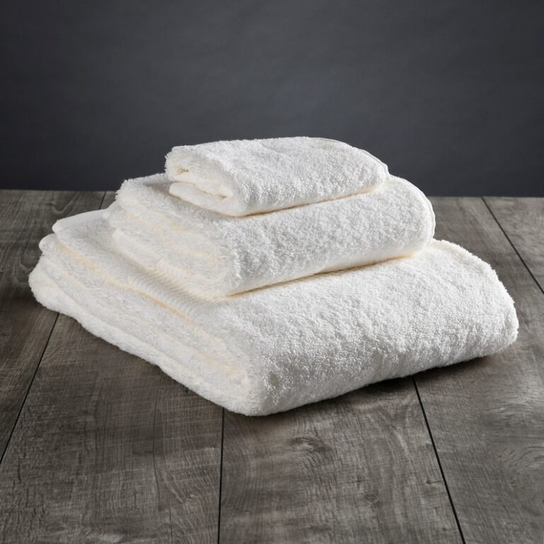 Stack of soft fluffy white bath towels folded on a wooden surface