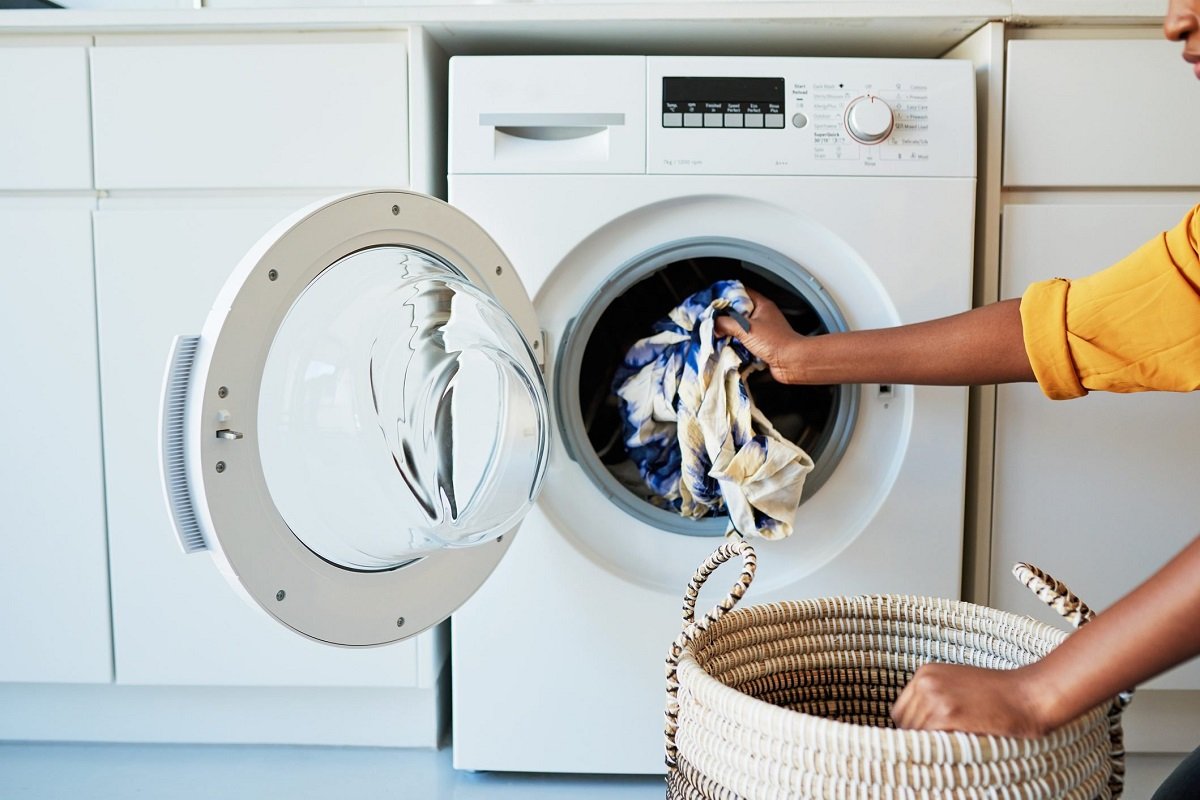 Person removing freshly washed laundry from a washing machine