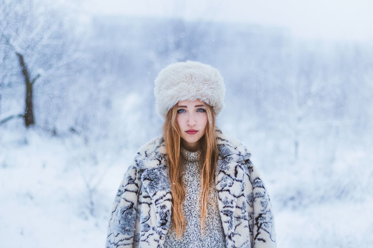 Woman in warm winter clothing standing in falling snow