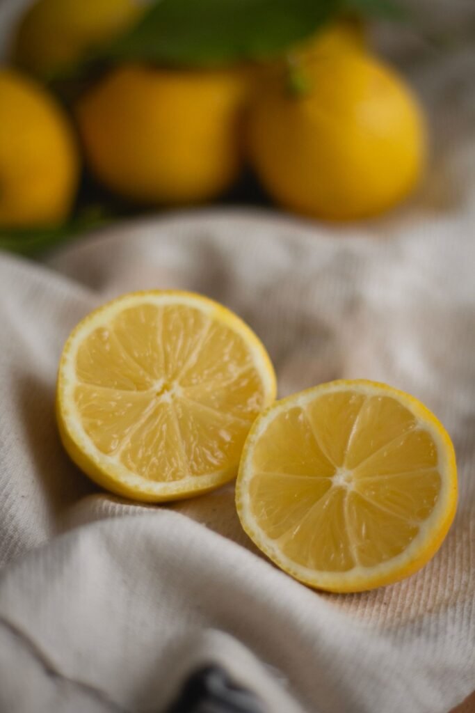 Fresh lemons with one cut in half resting on a grey cloth for natural kettle cleaning