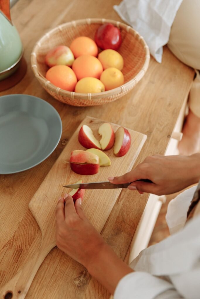 Person slicing fresh red apples into wedges on a wooden chopping board