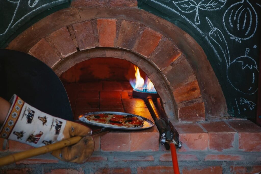 Pizza baking on a peel inside a hot oven with glowing heat