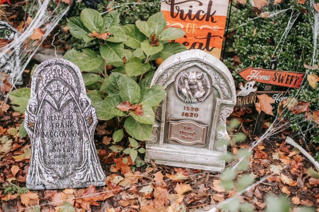 Foam tombstone Halloween decorations placed among autumn leaves in a garden