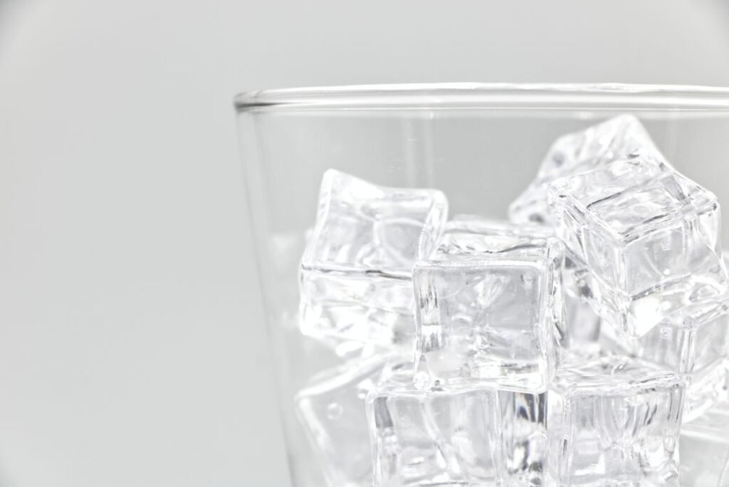 Glass filled with ice cubes for freezing spilled candle wax