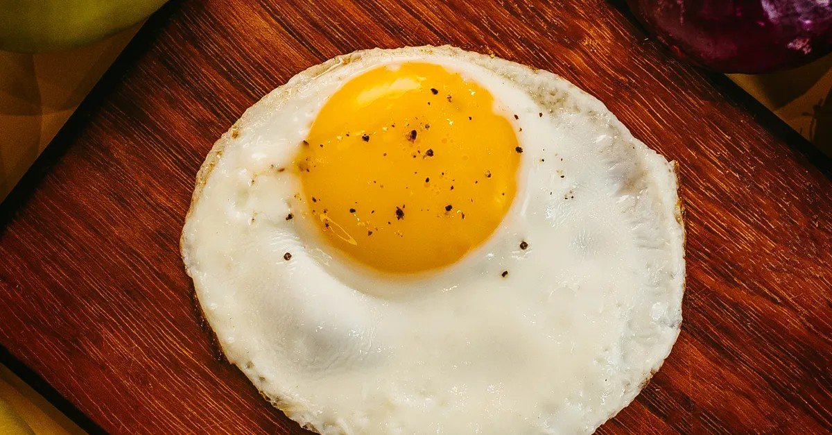 Perfectly cooked fried egg with runny yolk on a wooden board