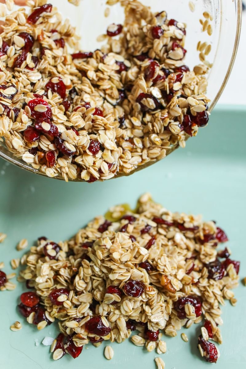 Oat and cranberry flapjack mixture being poured from a mixing bowl