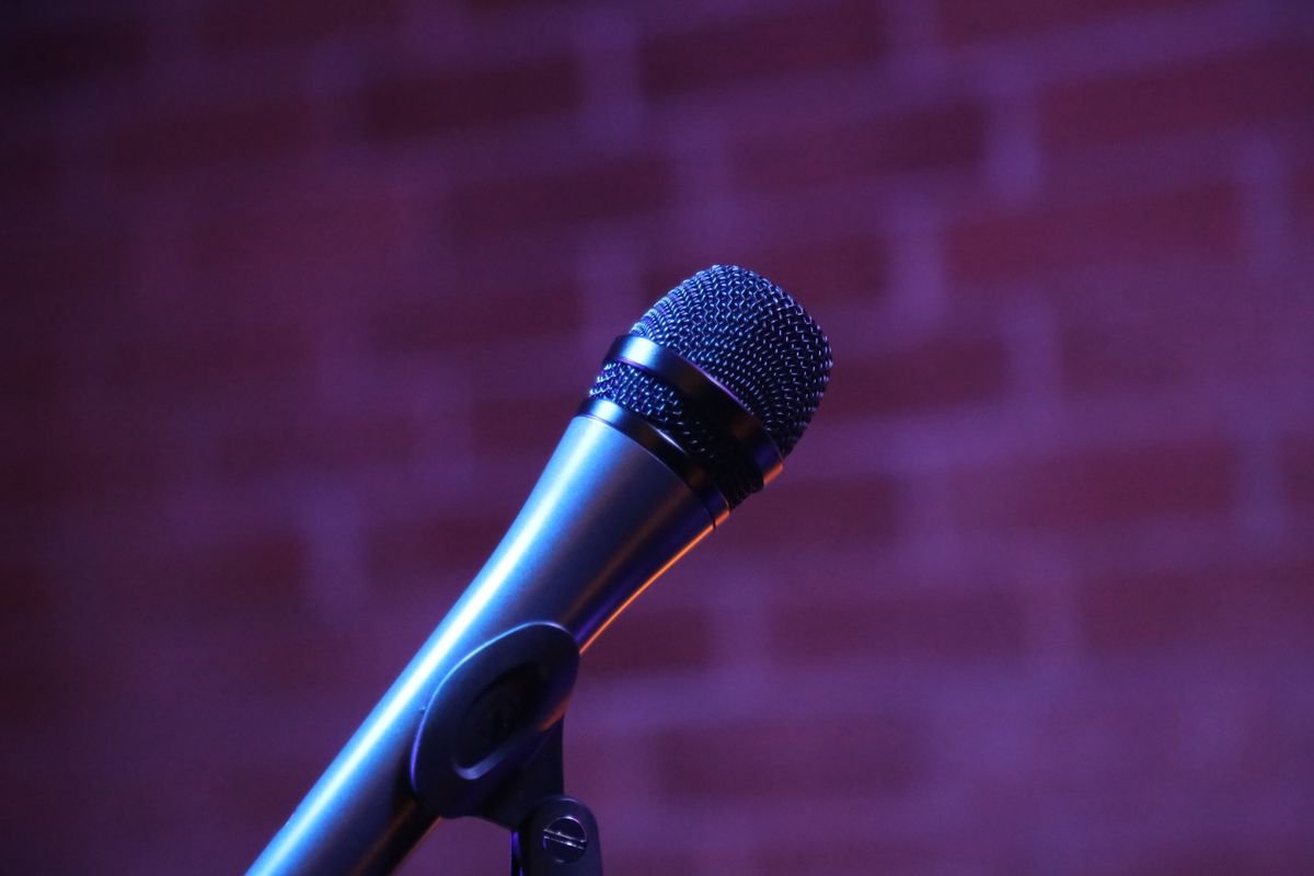 A vintage stage microphone glowing under a spotlight, a nod to Joanne McNally stand up comedy career
