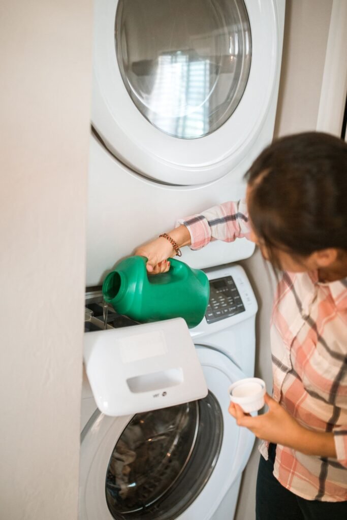 Woman pouring liquid detergent into a washing machine dispenser drawer