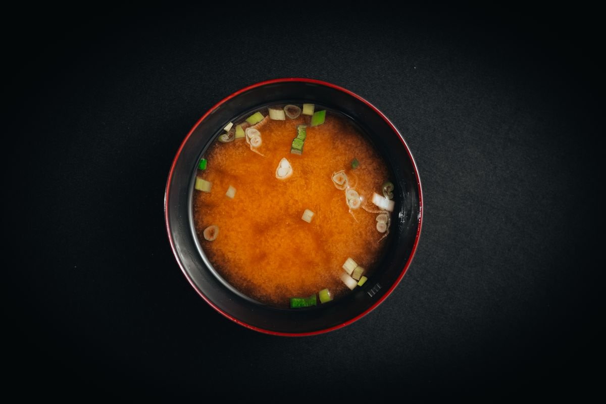 Overhead view of a bowl of red miso soup with chopped scallions