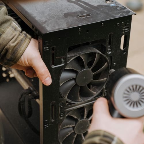 Cleaning dust from a computer cooling fan with an air blower