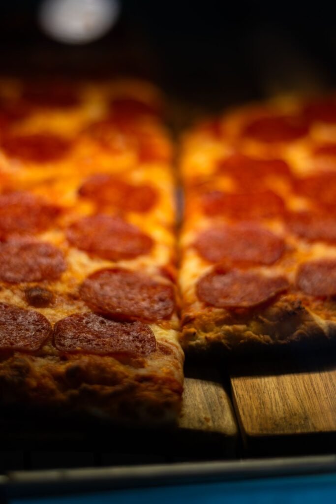 Close up of pepperoni pizza slices arranged on a wooden countertop ready to keep warm