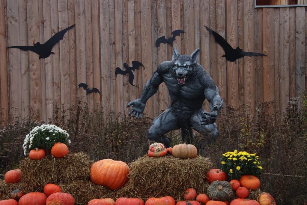Large werewolf Halloween prop surrounded by pumpkins and hay bales outdoors