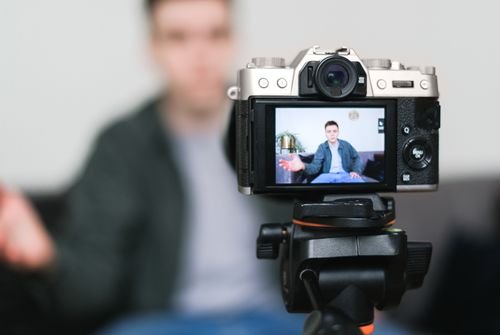 Camera on a tripod recording a video creator at home