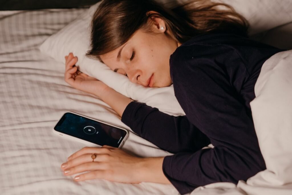Woman sleeping in bed with her smartphone on the pillow beside her