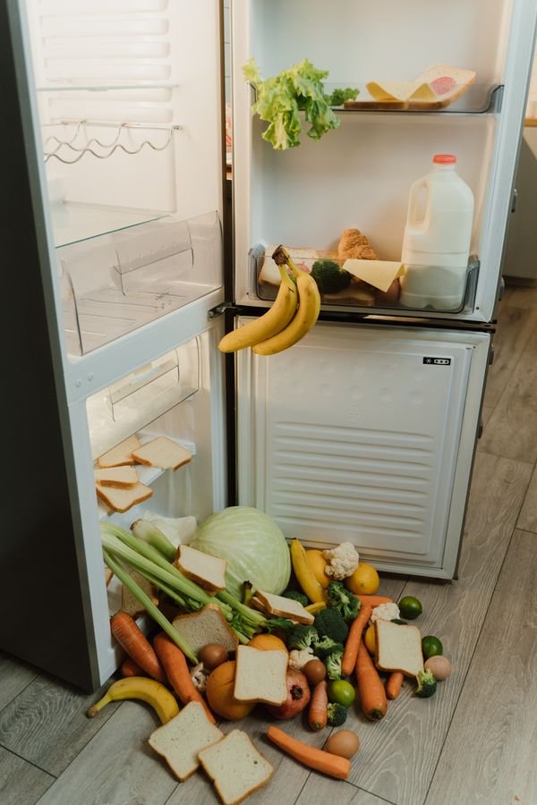 Refrigerator with fresh food and vegetables spilling out onto the floor