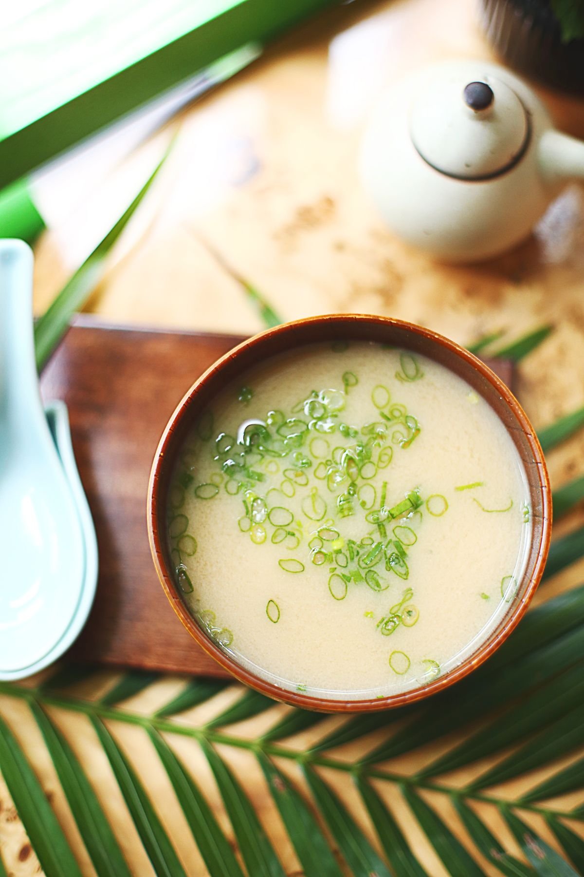 Bowl of white miso soup topped with fresh green onions