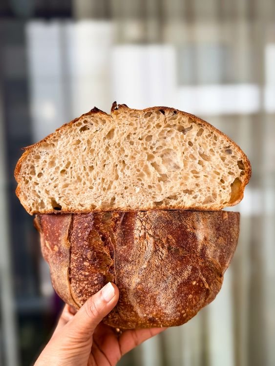 Hand holding a sliced sourdough loaf showing the airy crumb
