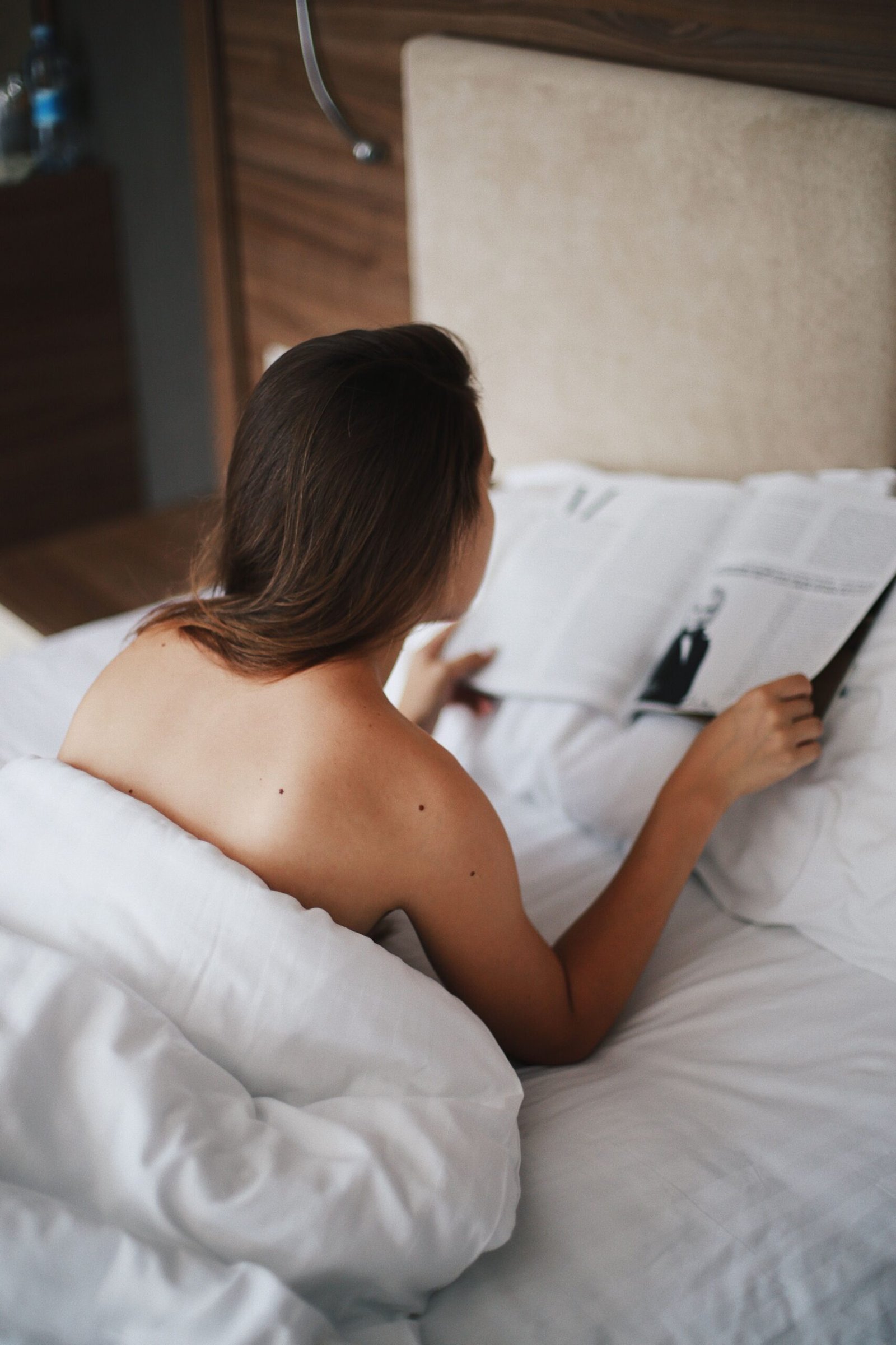 Woman relaxing in bed wrapped in a comfortable white duvet