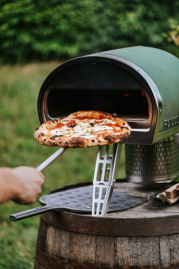 Person taking a freshly baked pizza out of the oven