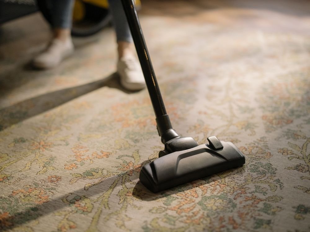 Person vacuuming a patterned carpet after cleaning a wax spill