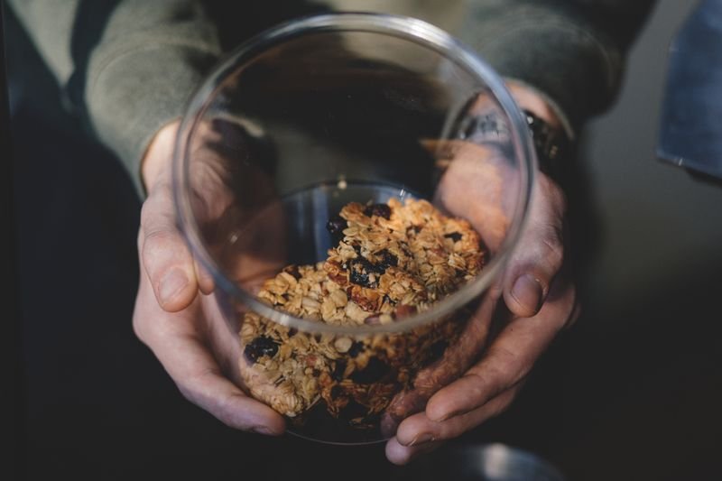 Hands holding a glass bowl of homemade oat granola