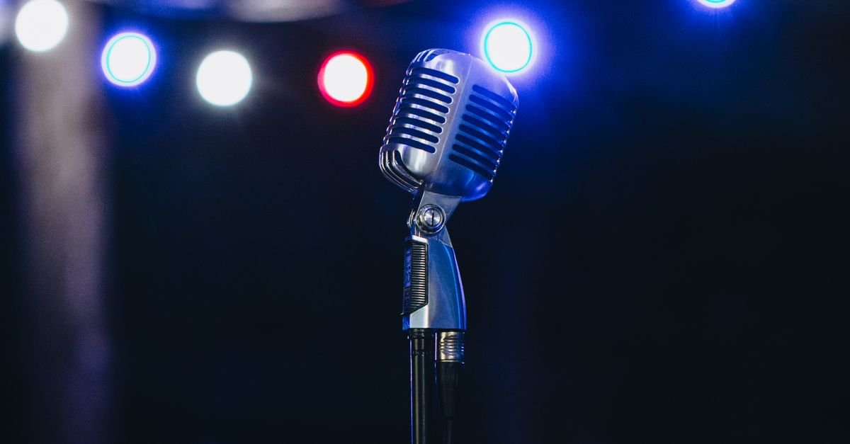 Microphone on a stage under bright lights, a nod to Maya Jama presenting career on Love Island and the BRIT Awards