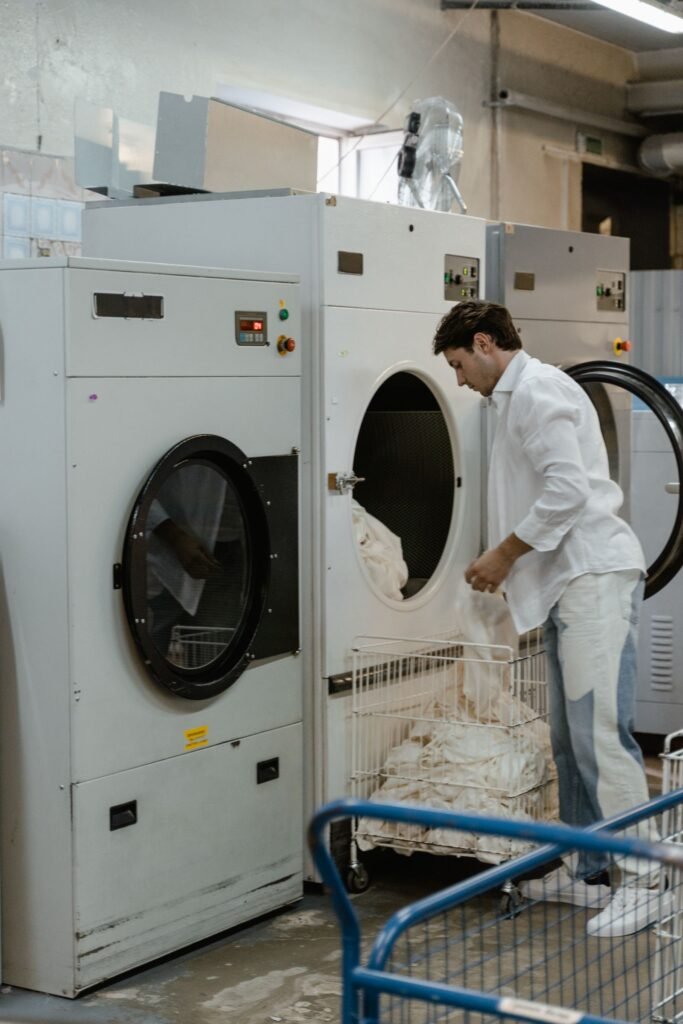Man loading clothes into washing machines at a laundromat