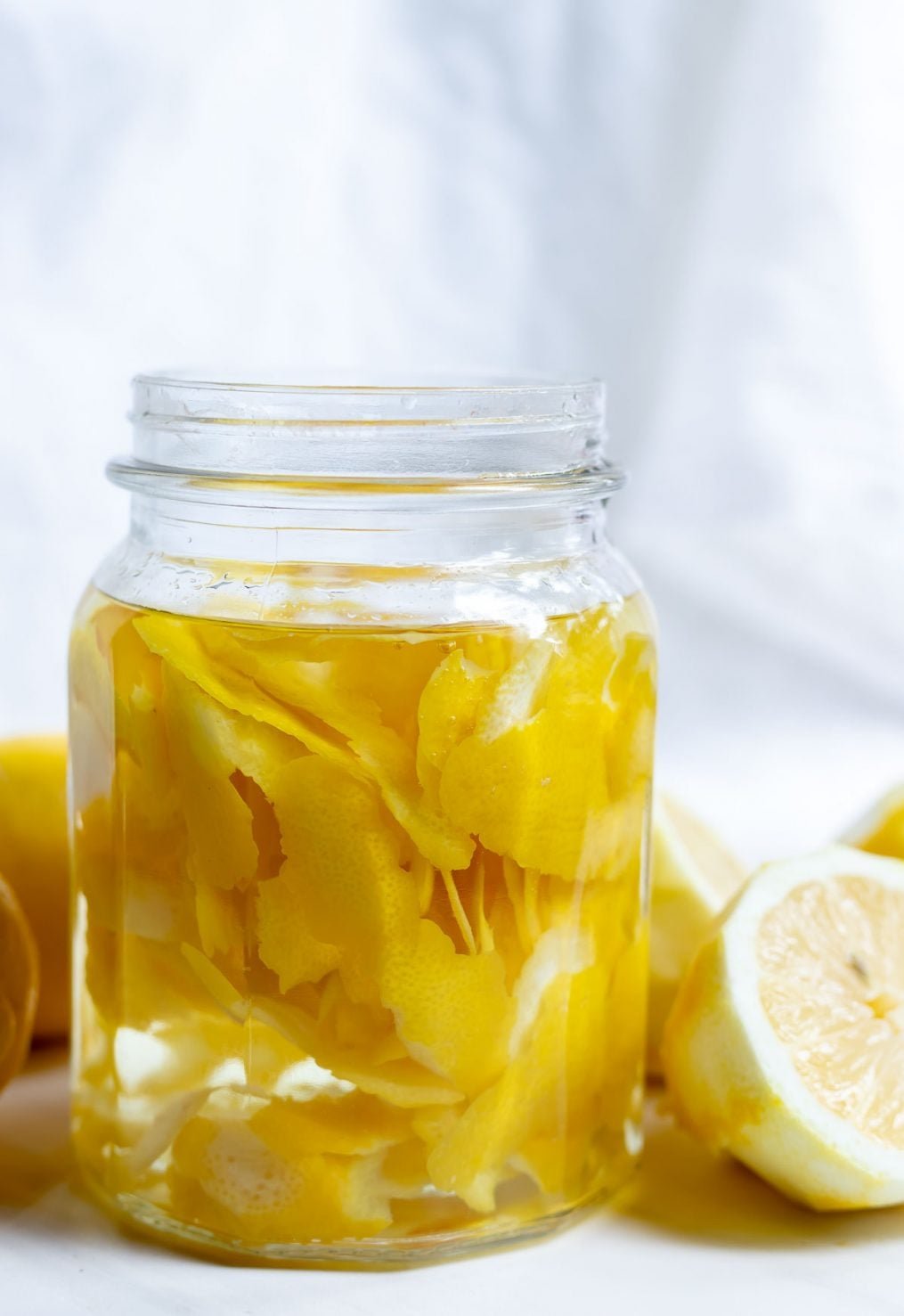 Lemon peels soaking in vinegar in a glass jar for microwave cleaning