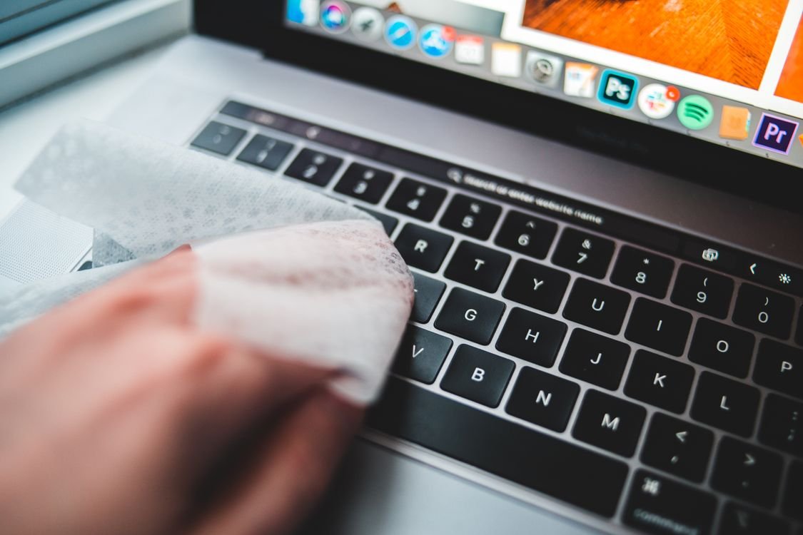 Hand wiping keyboard keys with a disinfectant wipe