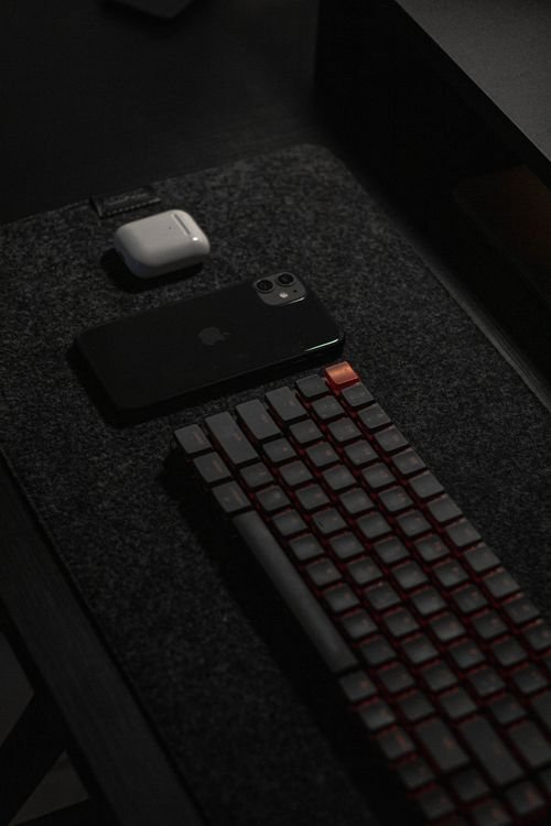 Clean mechanical keyboard on a dark desk mat next to a smartphone