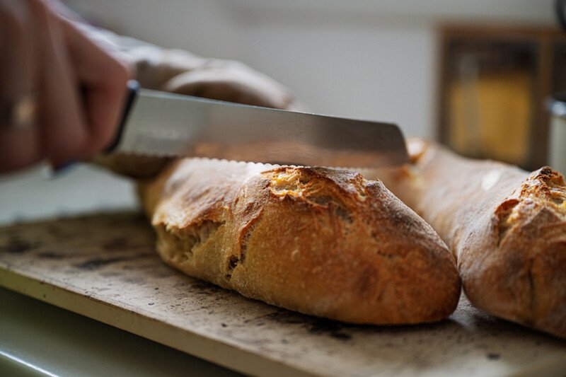Knife slicing into a freshly baked sourdough loaf on a board