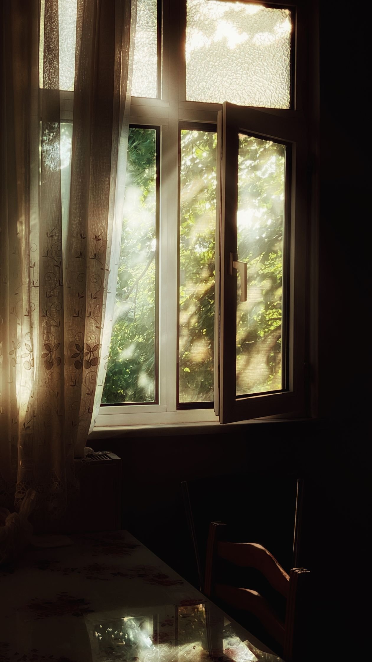 An open window with curtains letting fresh air and sunlight into a room